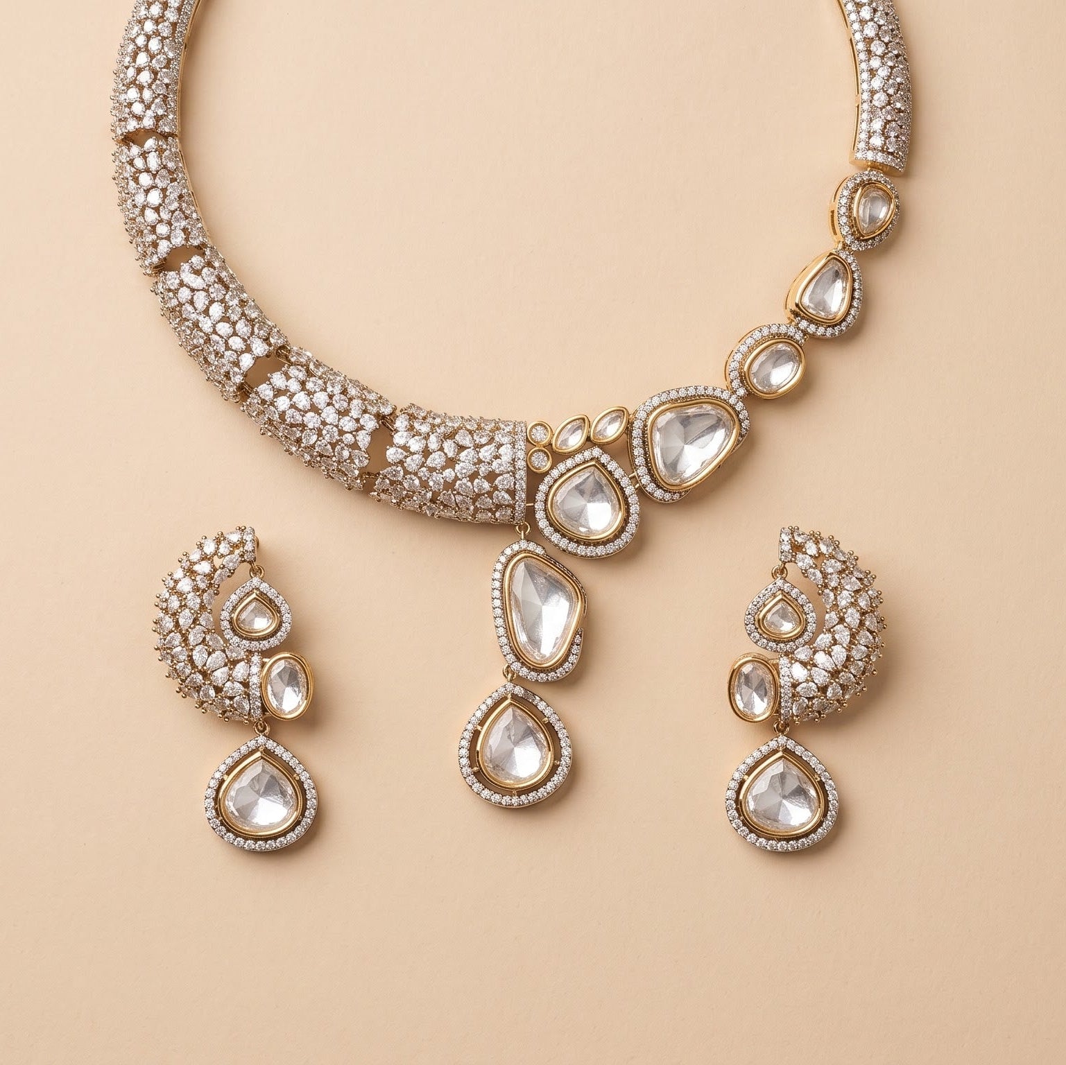Gold-toned traditional Indian jewelry set featuring a necklace, earrings, and a pendant, embellished with clear stones on a warm beige background.